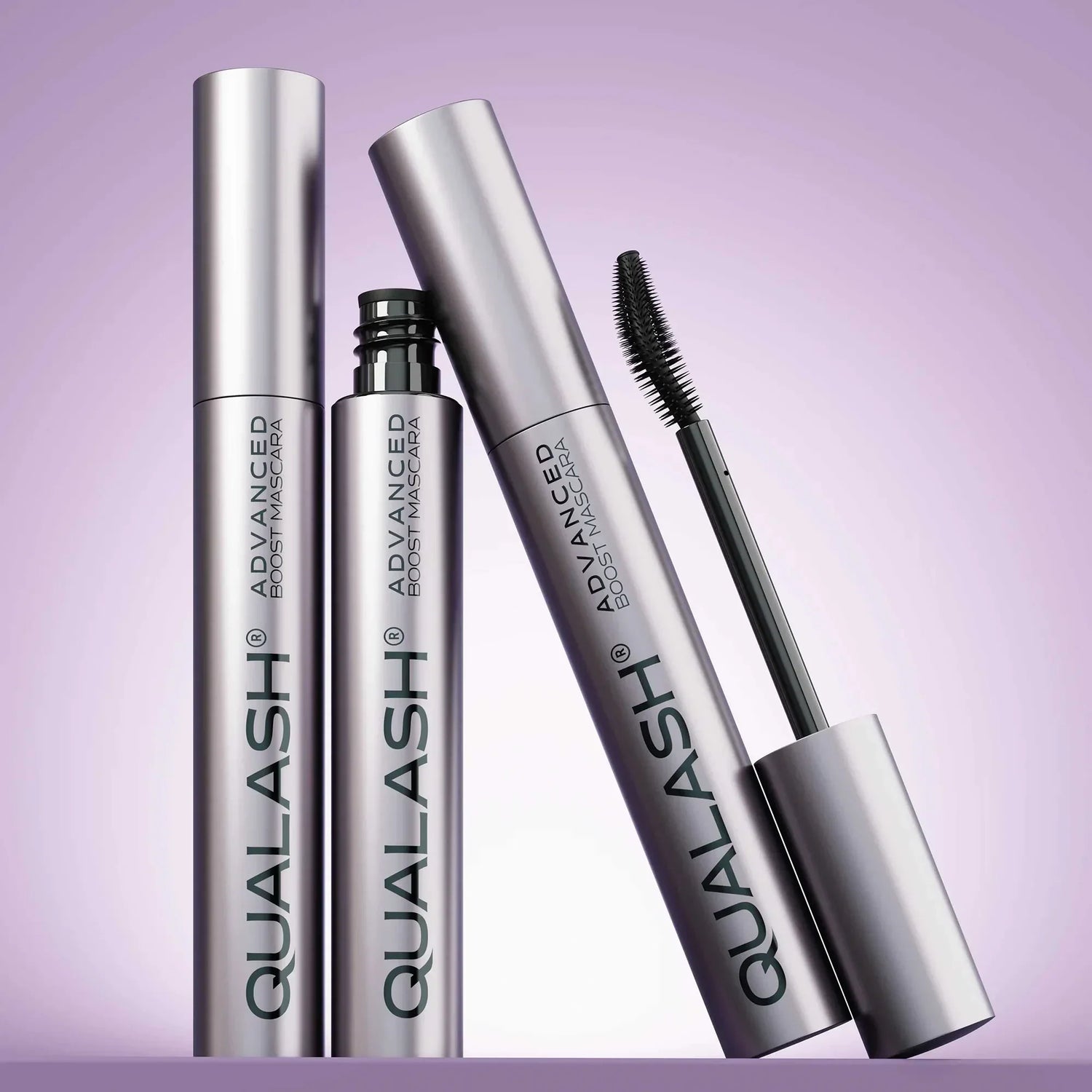Multiple QUALASH Curl &amp; Lift mascaras arranged creatively on soft purple background with focus on brush and tube